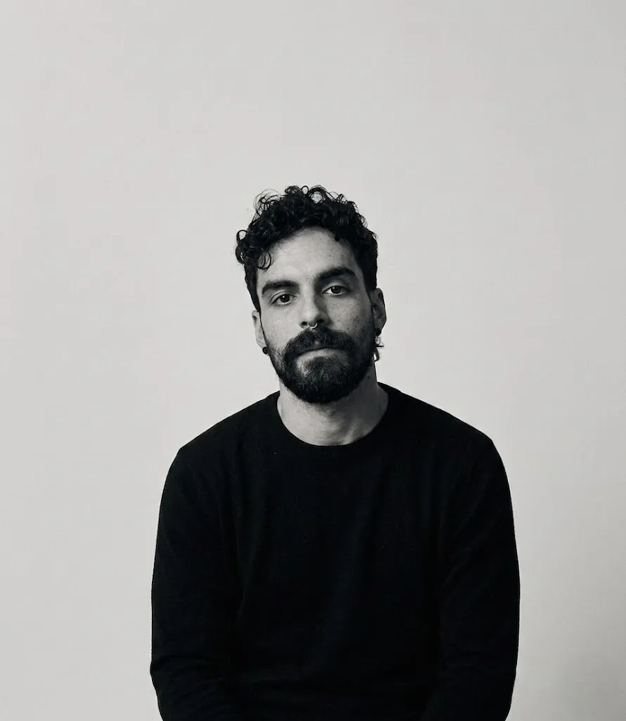Black and white portrait of Alv in a dark sweater against a plain light wall